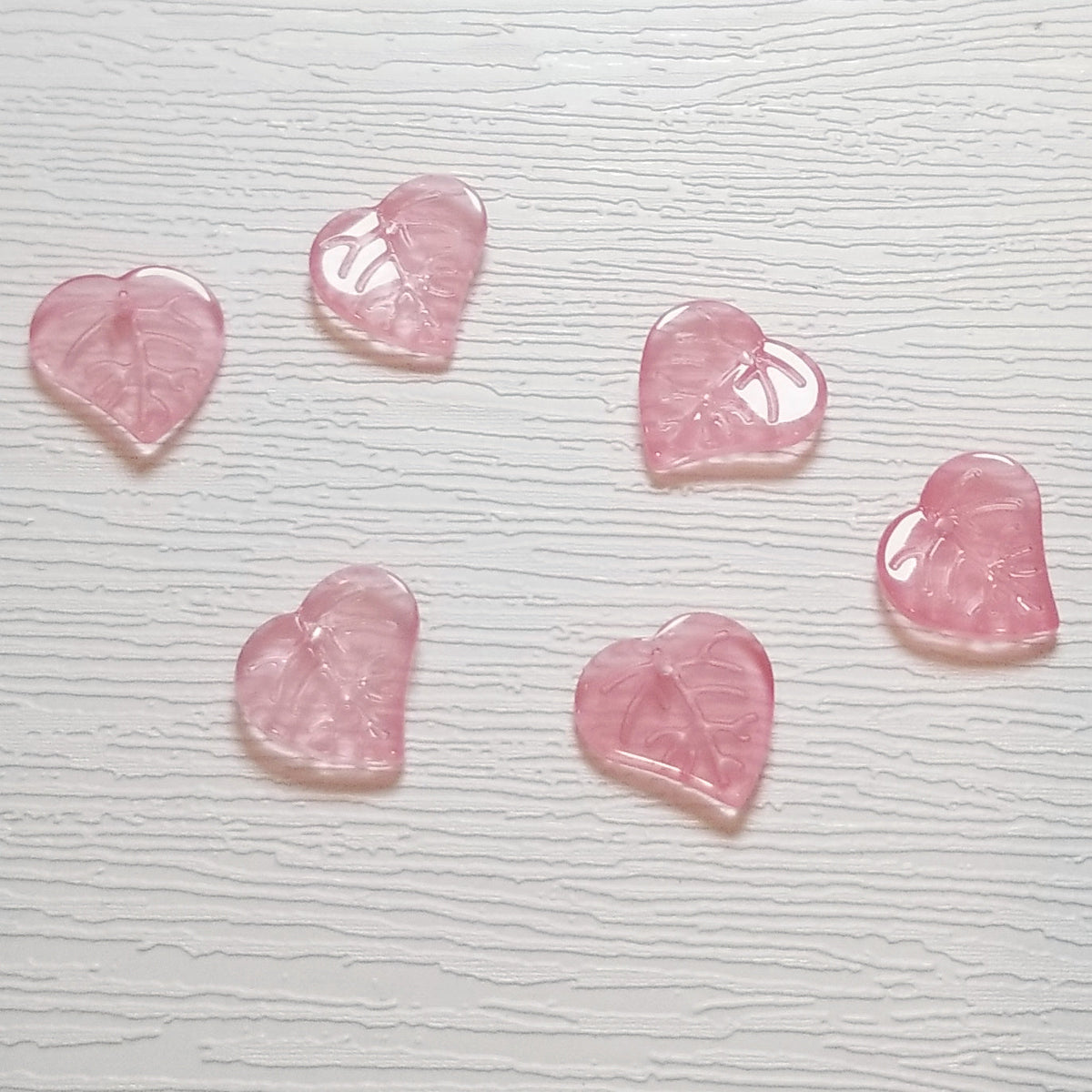 Rose pink premium glass leaf heart beads showing translucent color and leaf veining