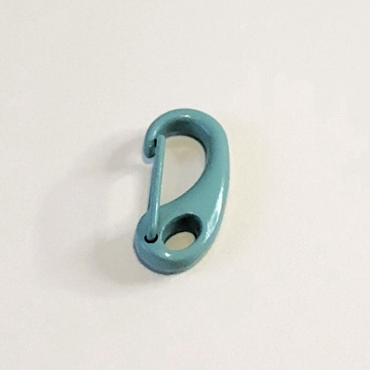 A small teal blue metal carabiner clip with a glossy finish, photographed on a plain off-white background.